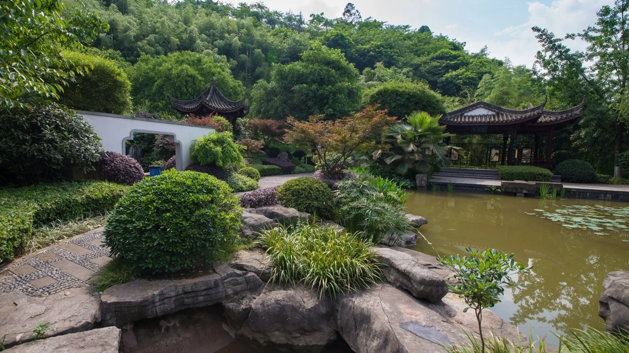 Taman lanskap dengan paviliun di lereng bukit dan kolam